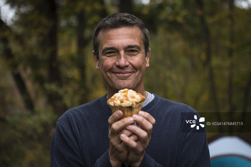 在森林里拿着纸杯蛋糕的中年男人图片素材