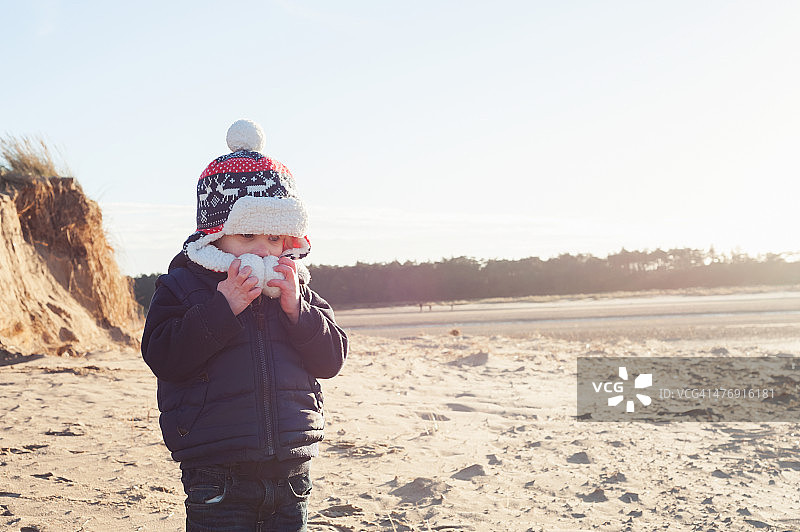 寒冷沙滩上保暖的男孩图片素材