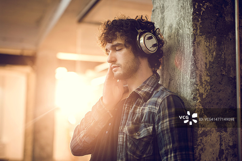 年轻男人闭着眼睛戴耳机听音乐图片素材