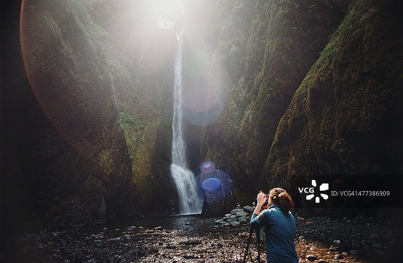女人在峡谷中拍摄瀑布图片素材