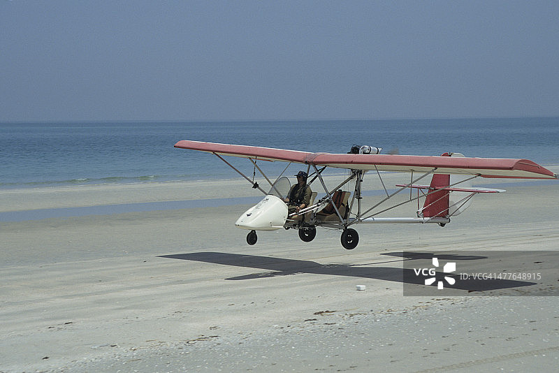 超轻型飞机在海滩上着陆图片素材