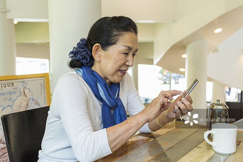 在咖啡馆使用手机的年长的日本女人图片素材