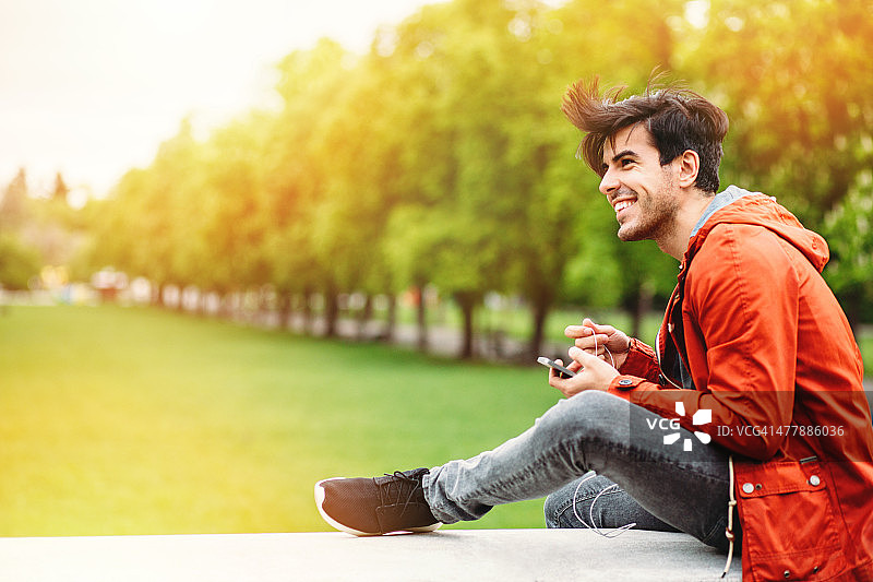 微笑年轻男人户外手持智能手机图片素材
