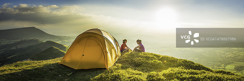 儿童在田园诗般的夏日日落山顶全景露营帐篷图片素材