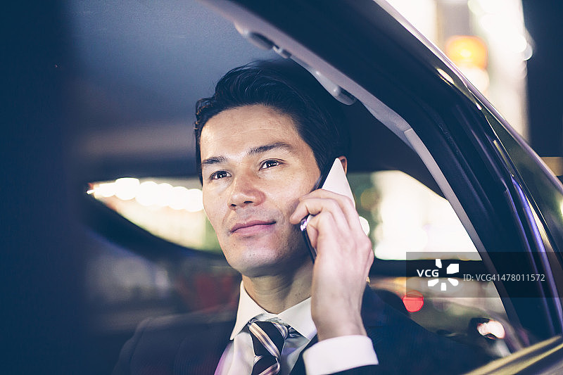 坐在汽车后座的亚洲商人图片素材