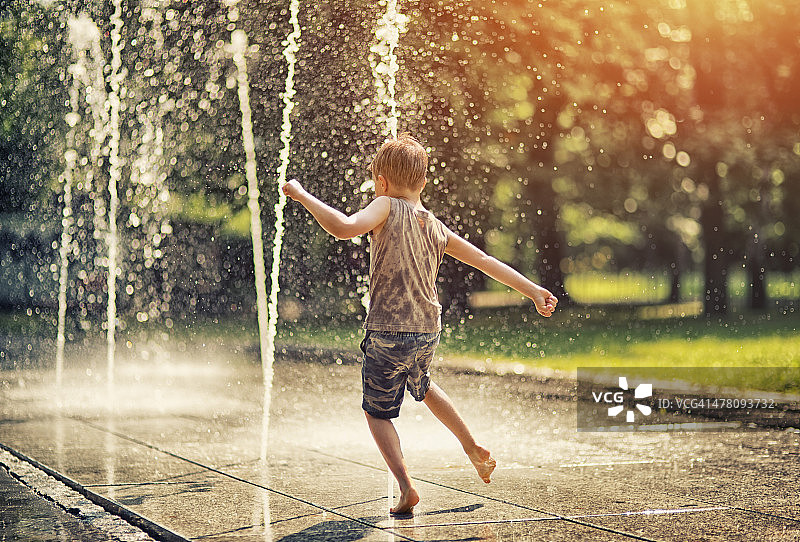 城市之夏：玩喷泉的小男孩图片素材