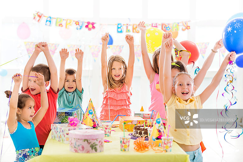 生日聚会上，欢快的孩子们举起了双手。图片素材