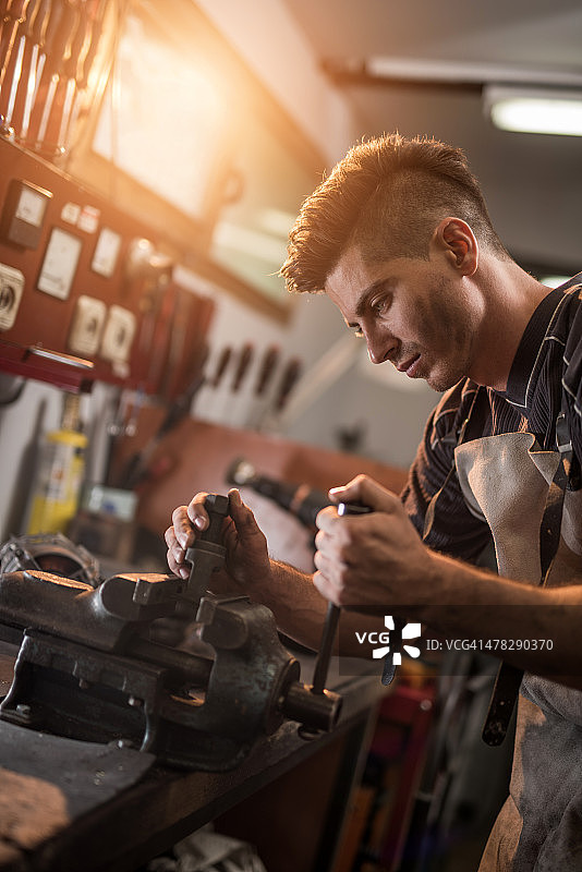 在车间使用虎钳的年轻机械师图片素材