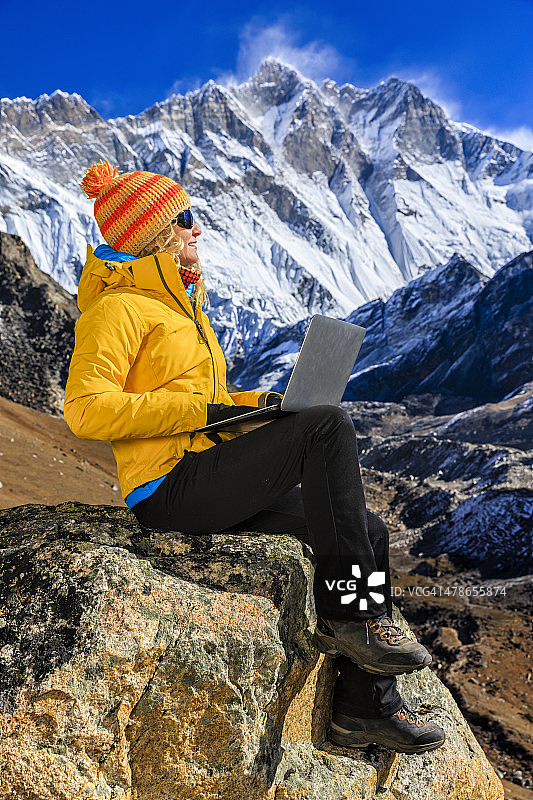 年轻女人在尼泊尔喜马拉雅山脉使用笔记本电脑图片素材