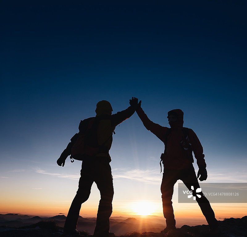 登山队在山峰上击掌庆祝图片素材