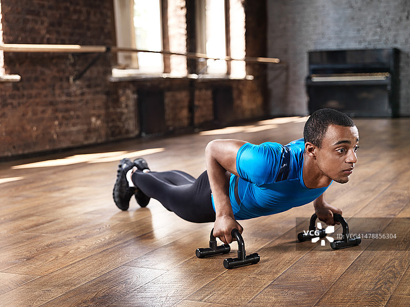 在高大健身房里做俯卧撑的健壮男人图片素材