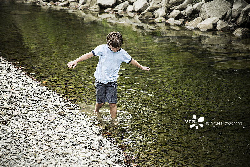 男孩在溪流中涉水图片素材