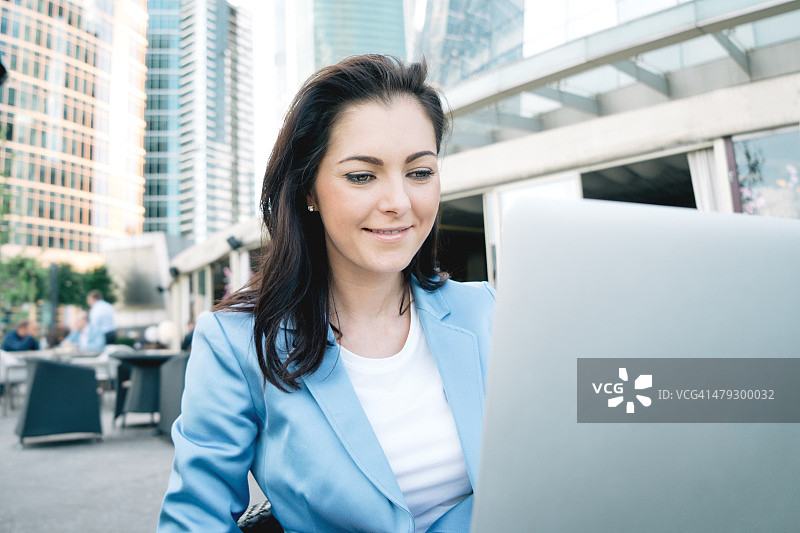 在咖啡馆用笔记本电脑工作的快乐女商人图片素材