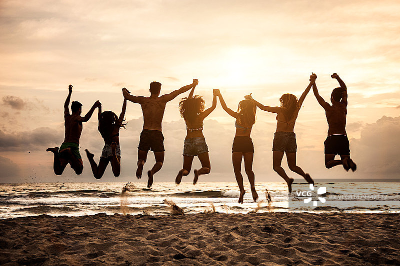 朋友们一起在海滩上跳跃图片素材