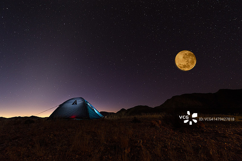 沙漠中点亮的帐篷上的红色满月和星星图片素材