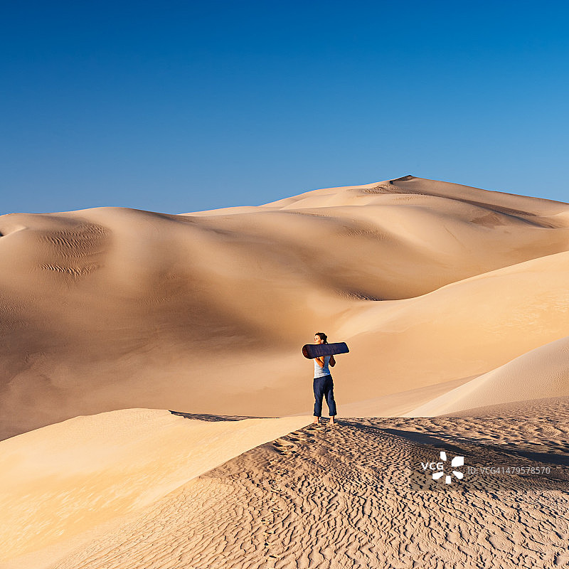 年轻女子在非洲撒哈拉沙漠滑沙图片素材