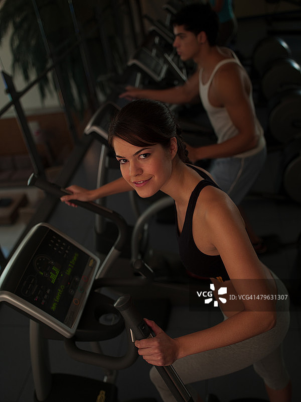 情侣在健身俱乐部使用踏步机锻炼图片素材