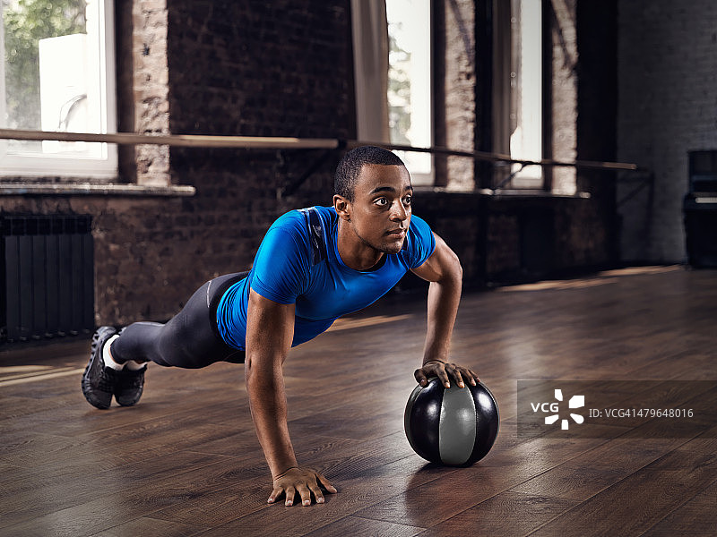 在高大健身房里做俯卧撑的健壮男人图片素材
