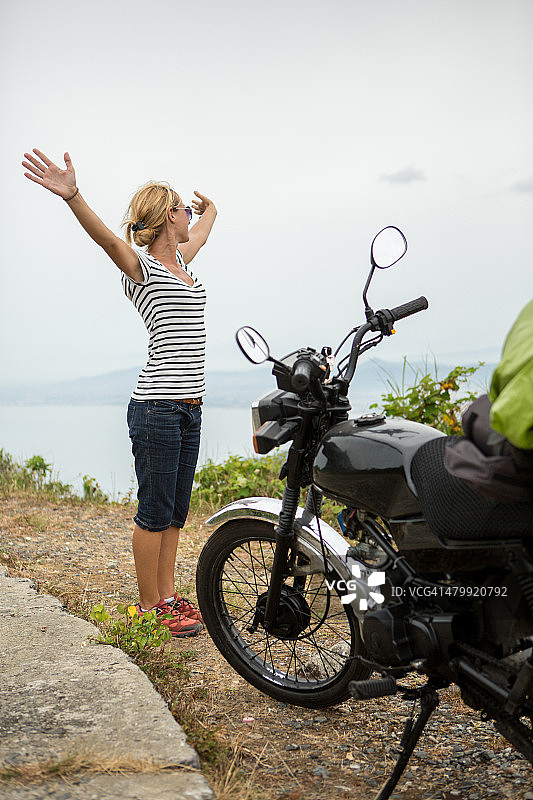 骑摩托车的女子在山顶的公路旅行图片素材