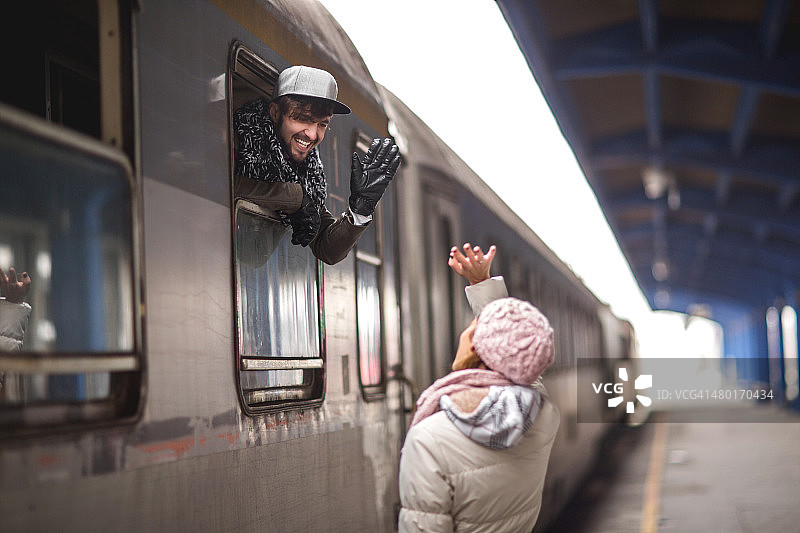 快乐的男人在火车上向朋友挥手图片素材