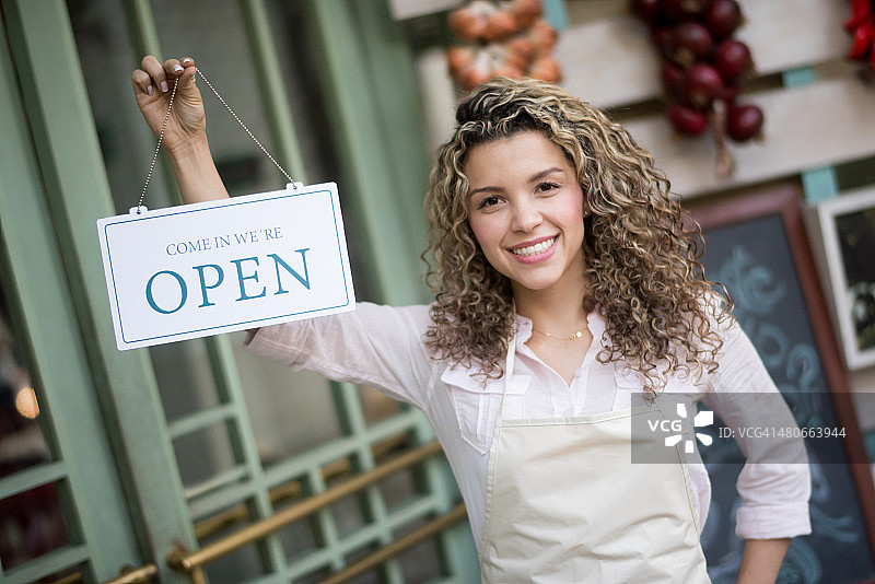 在餐厅拿着“营业中”标牌的女人图片素材