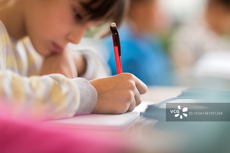 小学生在笔记本上写作的特写图片素材