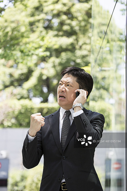 愤怒的日本中年商人正在打电话图片素材
