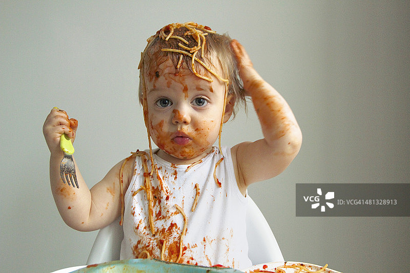 吃意大利面弄得一团糟的男婴图片素材