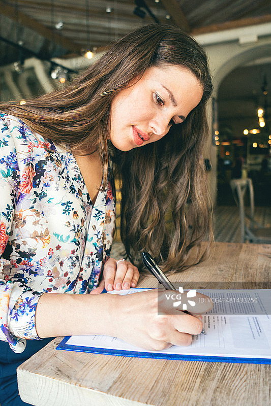 在咖啡馆里签署合同的漂亮女商人图片素材
