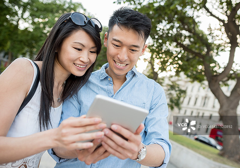 亚洲情侣在户外使用平板电脑图片素材