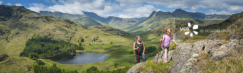 活跃的母女在田园诗般的山景全景中徒步旅行图片素材