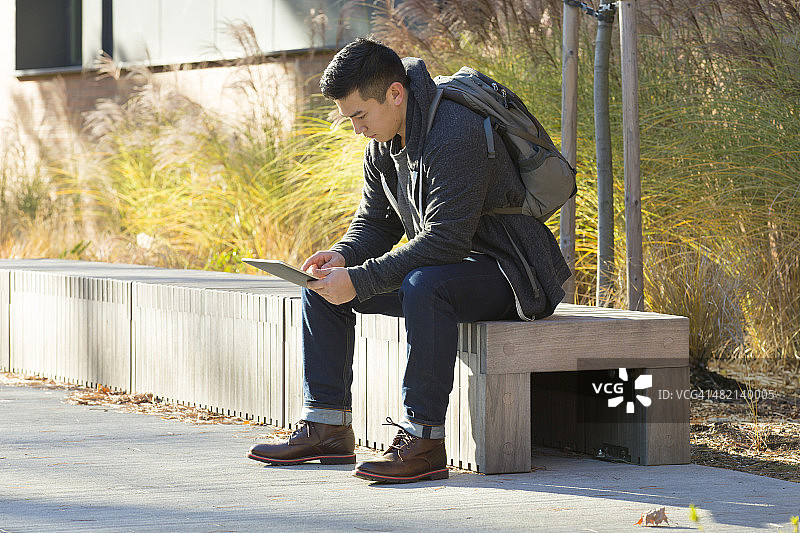 在校园里使用平板电脑的混血大学生图片素材