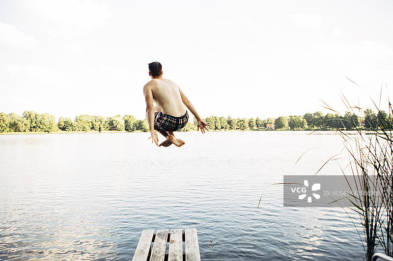年轻人从码头跳入湖中的背影图片素材