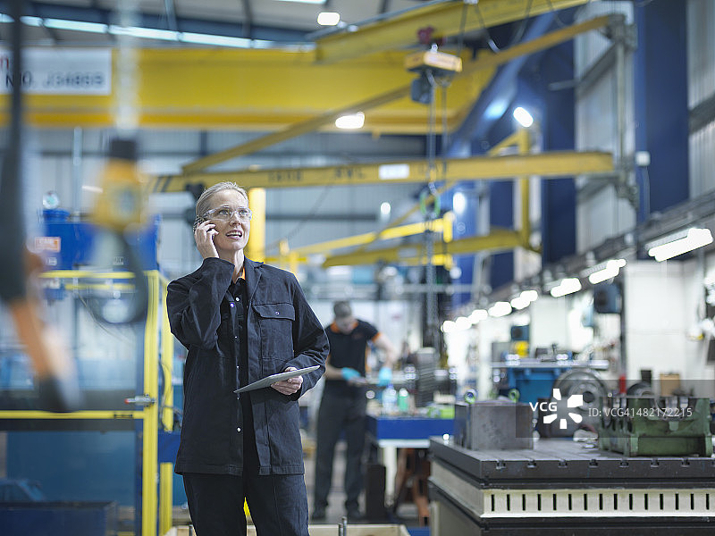 在工程工厂使用手机的女工人图片素材
