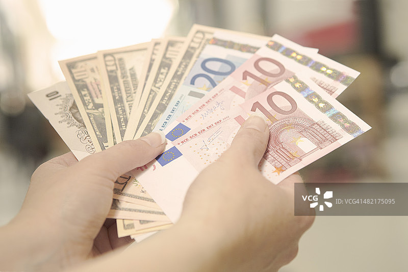 女人手持美元、英镑和欧元纸币图片素材