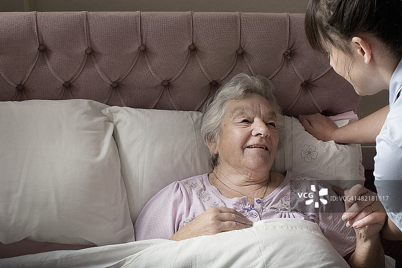 个人护理助理与卧床老年妇女聊天图片素材