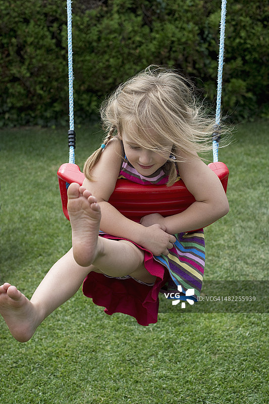专注的小女孩在花园里荡秋千图片素材