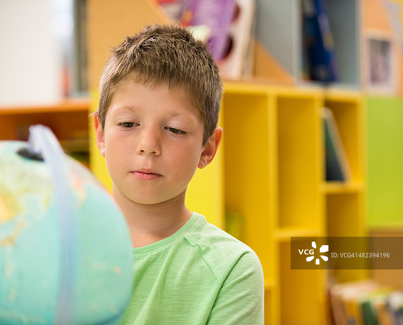 在图书馆看地球仪的小男孩图片素材