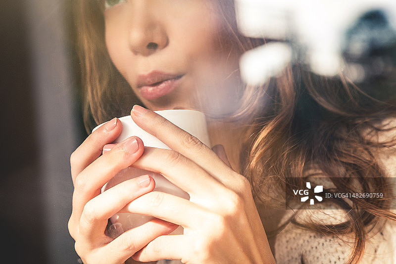 漂亮的女孩对着咖啡杯吹气图片素材