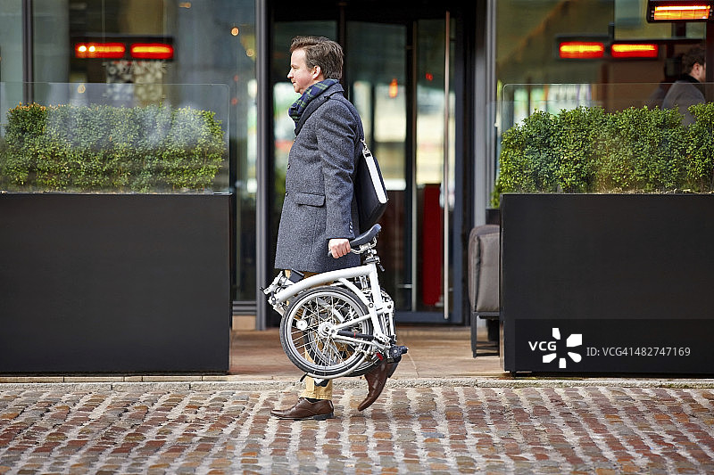 中年男商人 carrying 他的折叠自行车图片素材