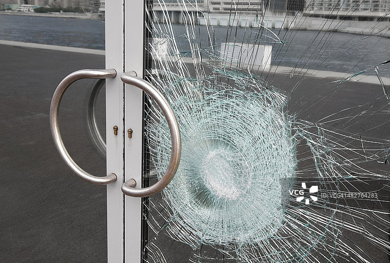 被故意破坏打碎的商业玻璃门上的破窗户图片素材