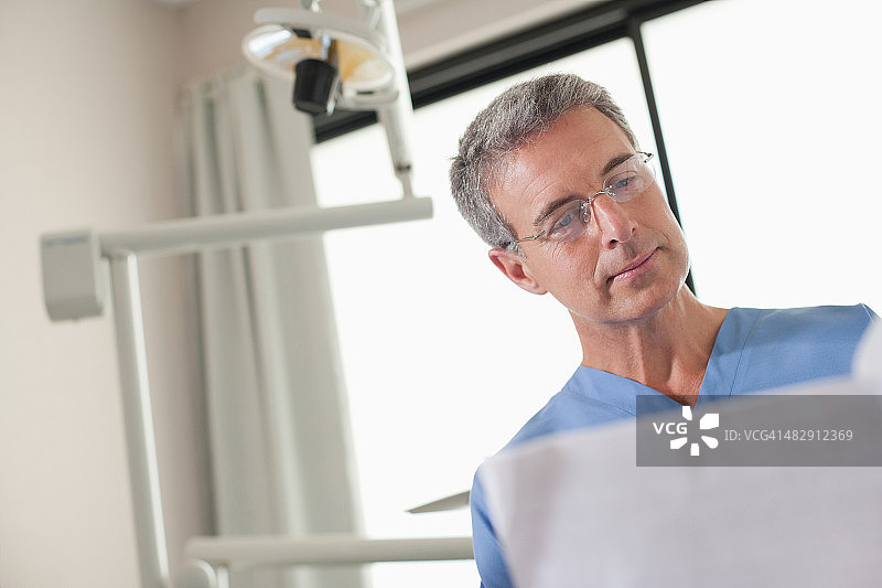 牙医站在诊室里查看图表图片素材