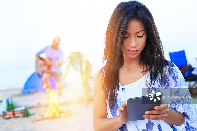 在海滩上使用平板电脑的亚洲女孩图片素材
