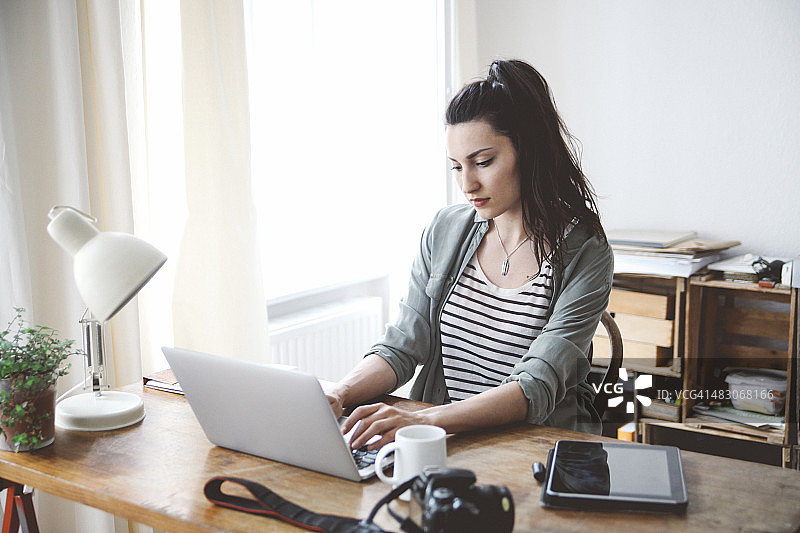 看笔记本电脑的年轻黑发女子图片素材