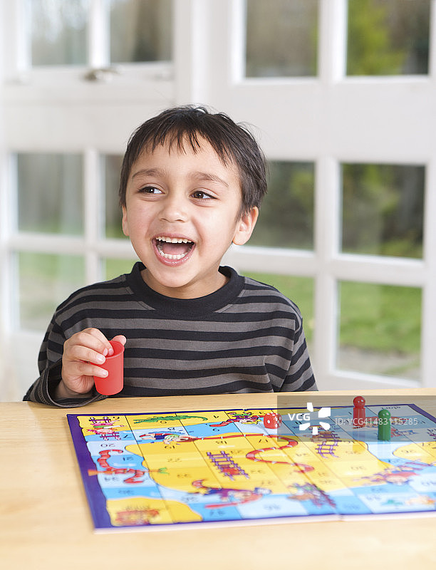 快乐的男孩玩棋盘游戏图片素材