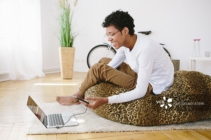 看笔记本电脑的欢笑非洲裔年轻男子，读卡器图片素材