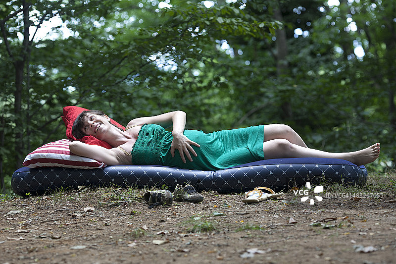 孕妇在森林里躺在充气床上休息图片素材