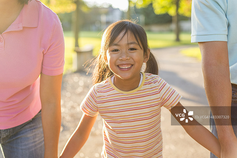 小女孩在父母中间行走图片素材