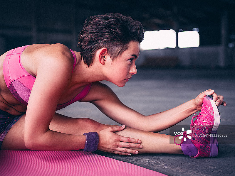 在运动垫上伸展的严肃少女图片素材