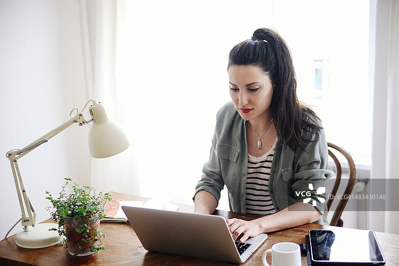 看笔记本电脑的年轻黑发女子图片素材